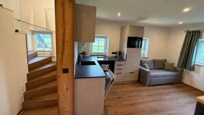 A modern kitchen with a built-in oven, a microwave, and a sink. There is a staircase leading to an upper level. - Vacation Rental in Salzburg (Salzburg)