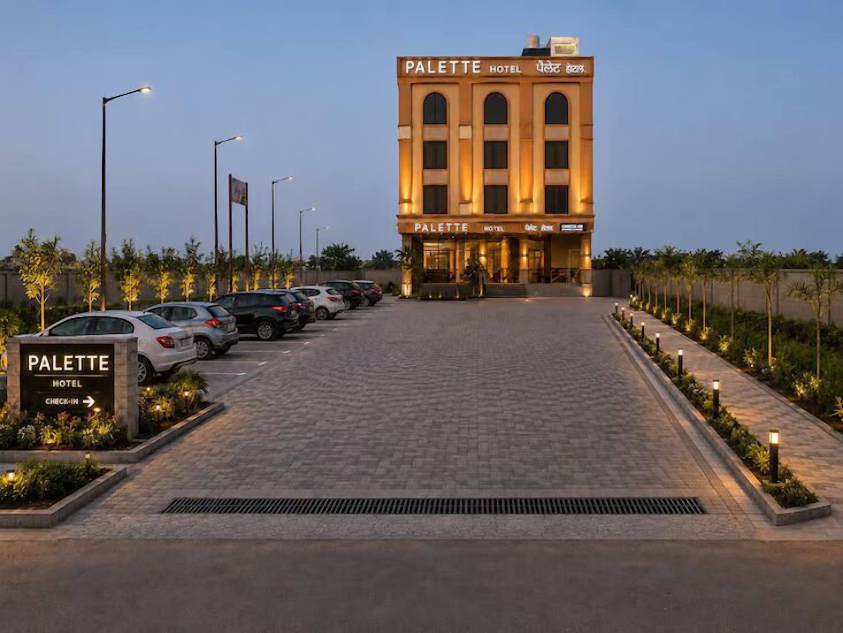 A hotel entrance with a check-in sign, a parking lot with multiple cars, and a building with the name 'PALETTE HOTEL' on the facade.