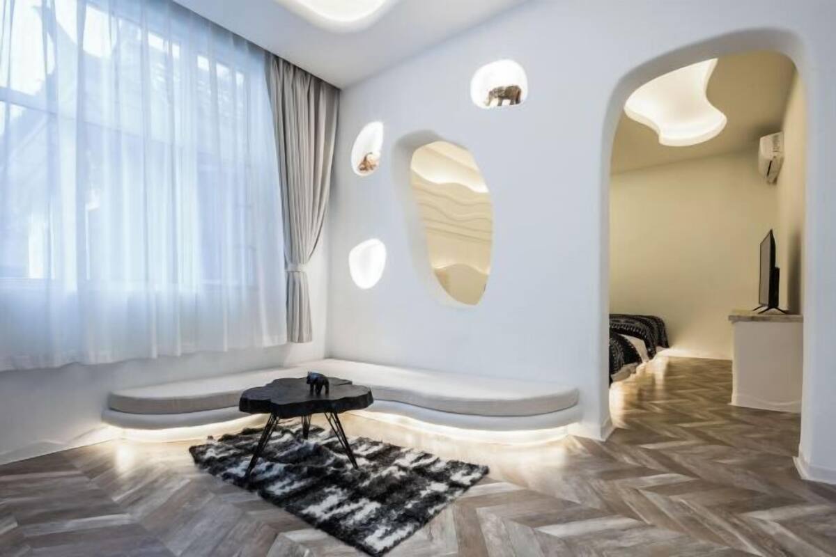 A modern room with a large window, a black sofa, a small table, and a patterned rug.
