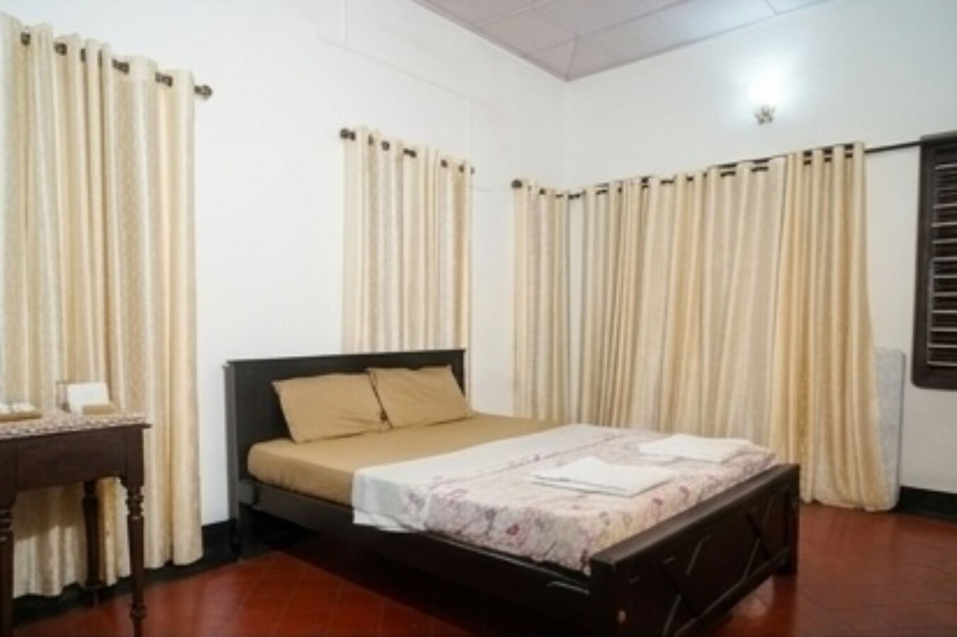 Une chambre à coucher avec un lit, des rideaux, une table de chevet et une fenêtre avec des stores.