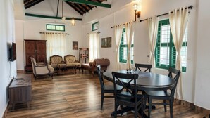 Una habitación con una mesa de comedor, sillas, un conjunto de sofás, un mueble de madera y una televisión.