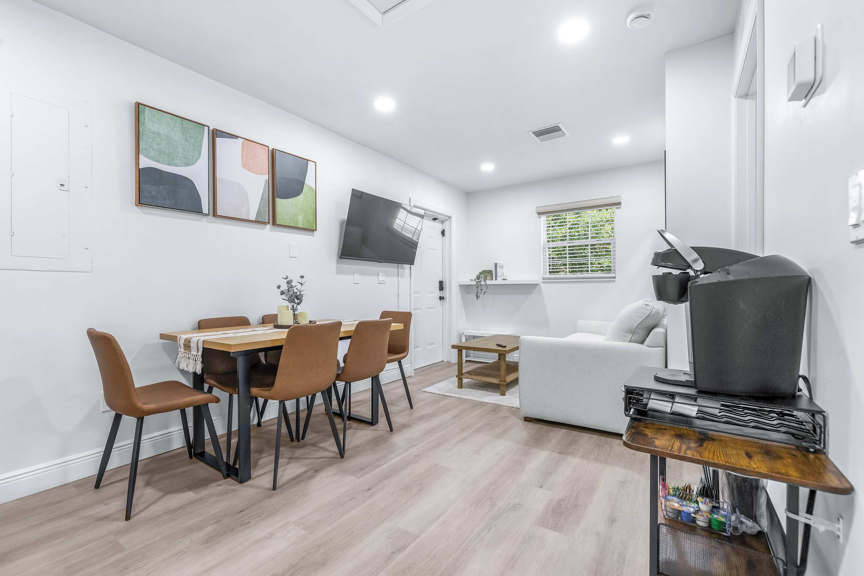 A modern living room with a dining area, a sofa, a TV, and a coffee table.