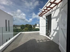 A rooftop terrace with a view of the city, a pergola, and a glass railing. - Lavi Zoli Stunning Private Villa in Grand Bay (Grand Baie)