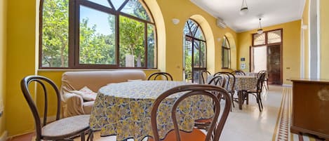 A dining area with round tables, chairs, and a sofa.