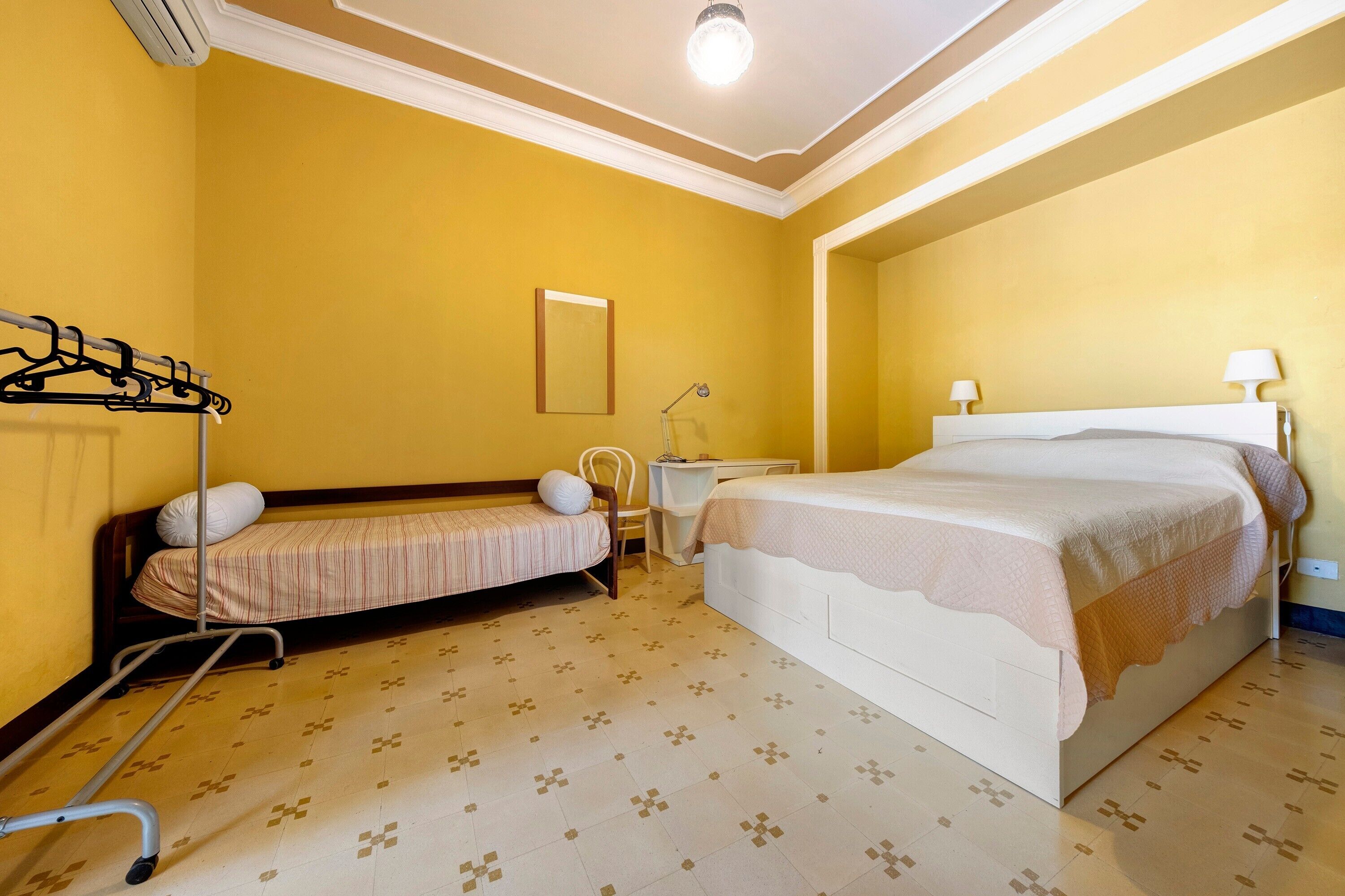 Une chambre d’hôtel avec un lit, une chaise, un bureau et un porte-manteau.