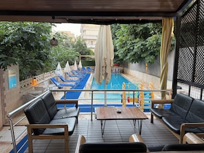 A poolside area with lounge chairs, a table, and a view of the pool. - Güldal Hotel (Marmaris)