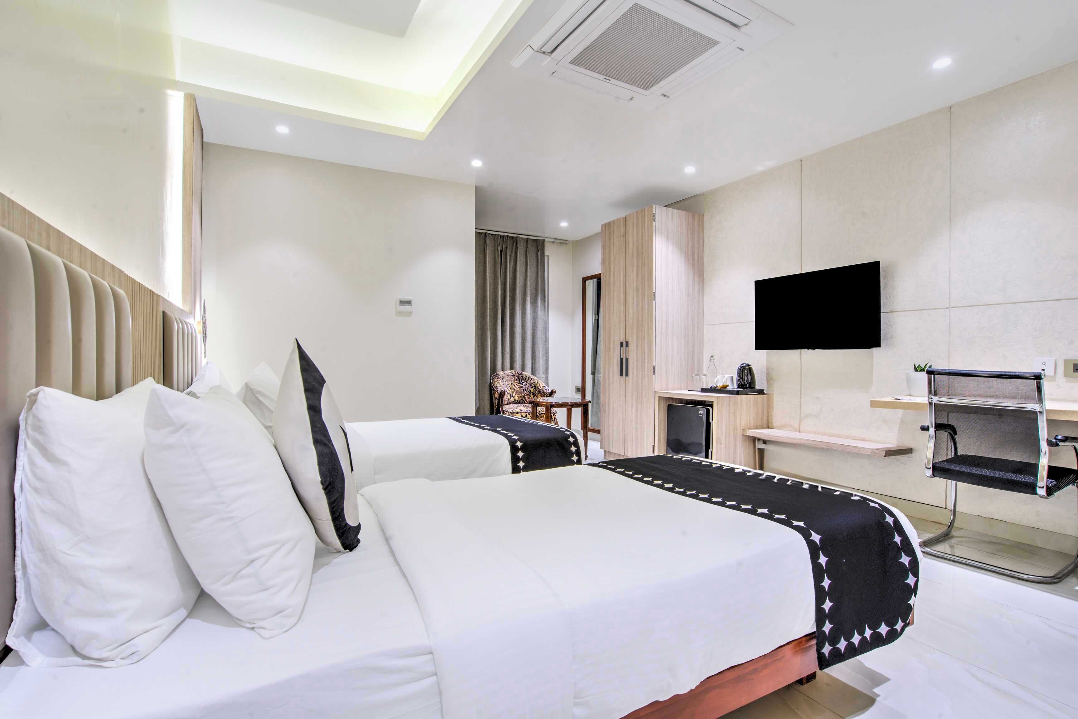 A hotel room with two beds, a TV, a desk, and a chair.