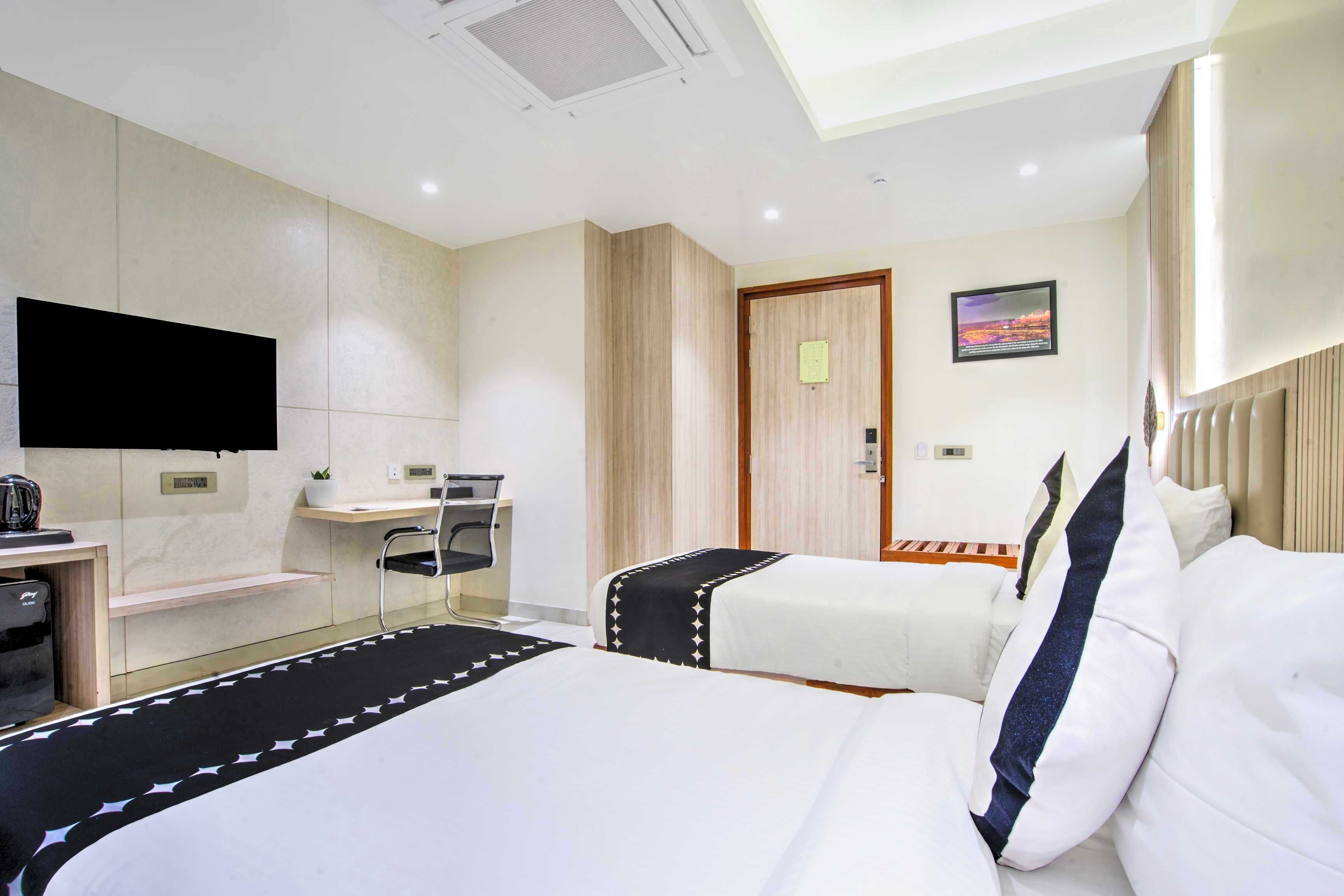Habitación de hotel con dos camas, un escritorio, una silla, un televisor y un cuadro en la pared.