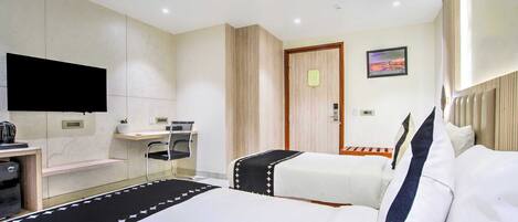 Habitación de hotel con dos camas, un escritorio, una silla, un televisor y un cuadro en la pared.