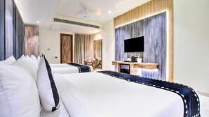 Una habitación de hotel con dos camas, un escritorio, un televisor y un ventilador de techo.