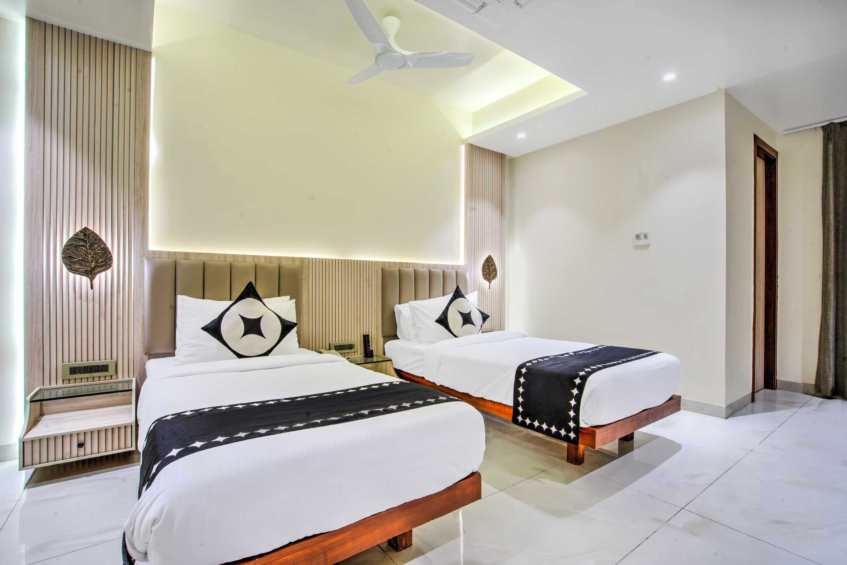 A hotel room with two beds, a ceiling fan, a bedside table, and a nightstand.