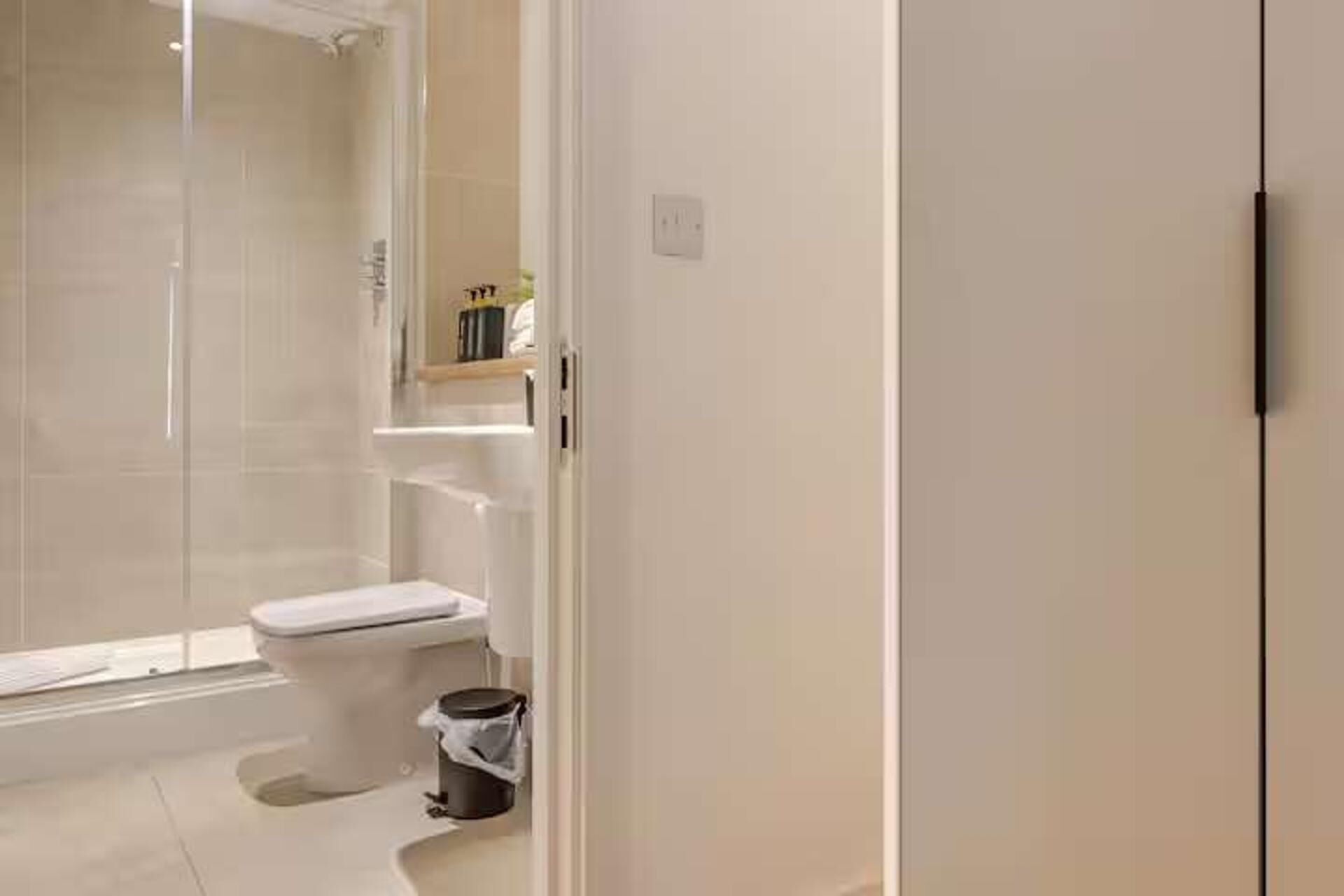 Une salle de bain avec des toilettes, une douche et une petite poubelle.