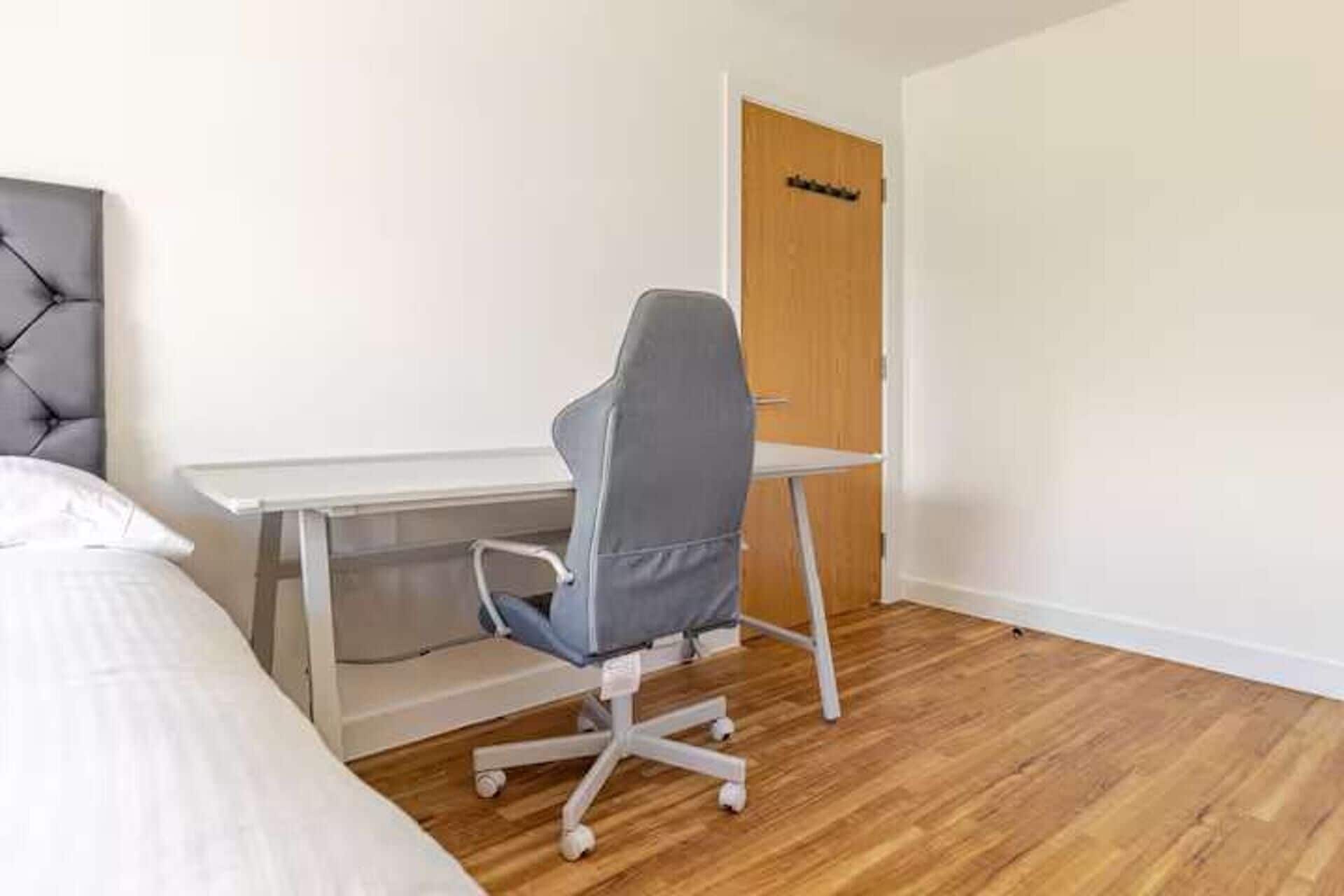 A bedroom with a bed, a desk, and a chair.