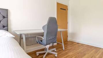 A bedroom with a bed, a desk, and a chair.