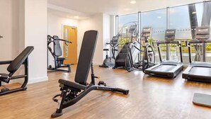 A gym with cardio machines, weight equipment, and a large window. - Cosy City Apartment in Manchester (Manchester)