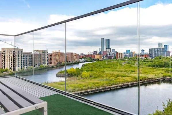 A modern building with a glass facade overlooking a river and cityscape. - Cosy City Apartment in Manchester (Manchester)