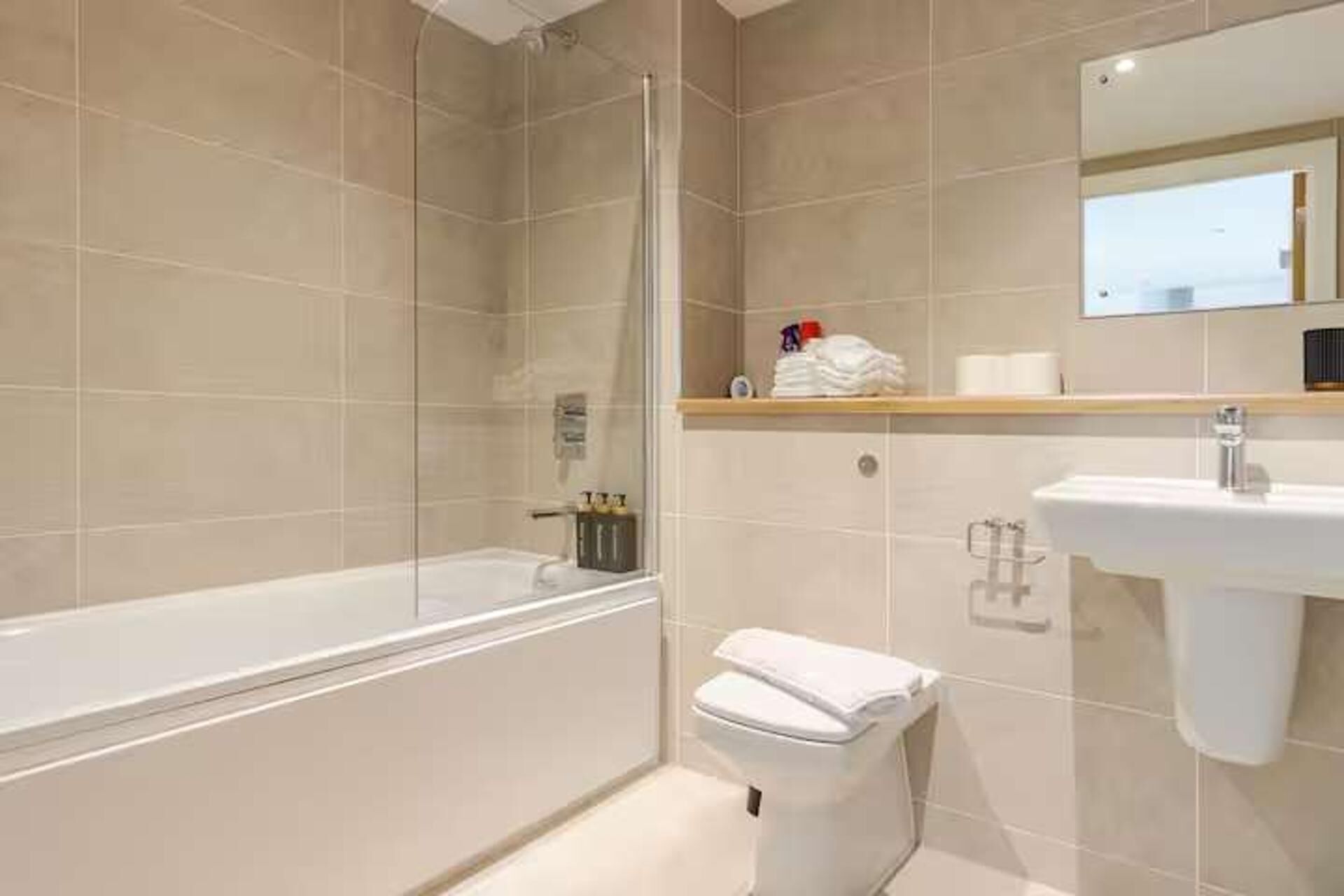 A modern bathroom with a glass-enclosed shower, a white toilet, and a sink.