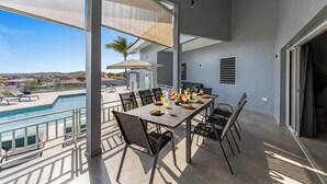 Eine Außenpatio mit Pool, einem Esstisch und Blick auf die umliegende Landschaft.