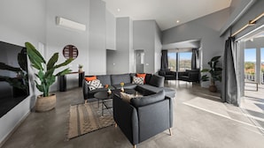 Ein modernes Wohnzimmer mit einem Ecksofa, einem Couchtisch und einer großen Küstertopf-Pflanze.