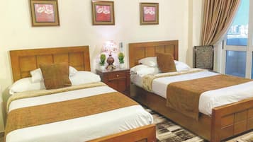 Habitación de hotel con dos camas, una mesita de noche con lámpara y una ventana con cortinas.