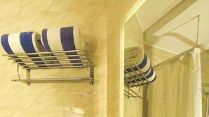 Un baño con lavamanos, espejo, toallero y zona de ducha.