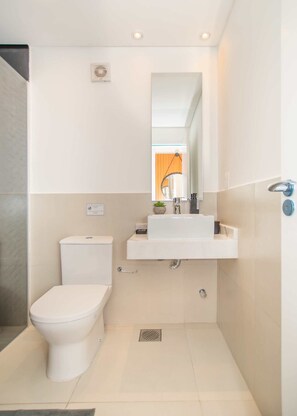 A modern bathroom with a toilet, a sink, and a mirror. - Corporate Stays Lumiere del Sol (Asunción)