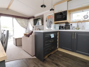 A compact kitchen with a microwave, sink, and a dining area with a sofa.