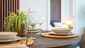 Ruokapöytä, jossa on kulho, kaksi viinilasia ja ruukussa oleva kasvi.