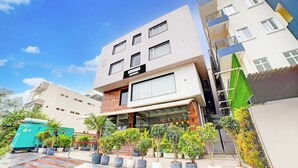 Un edificio de varios pisos con un letrero que dice 'PALETTE' en la planta baja, plantas en macetas y una escalera que lleva a la entrada.