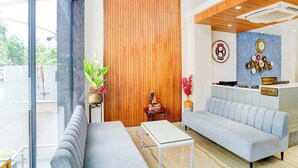 Un área de recepción moderna con un panel de madera, una recepción, un sofá y una pequeña mesa.