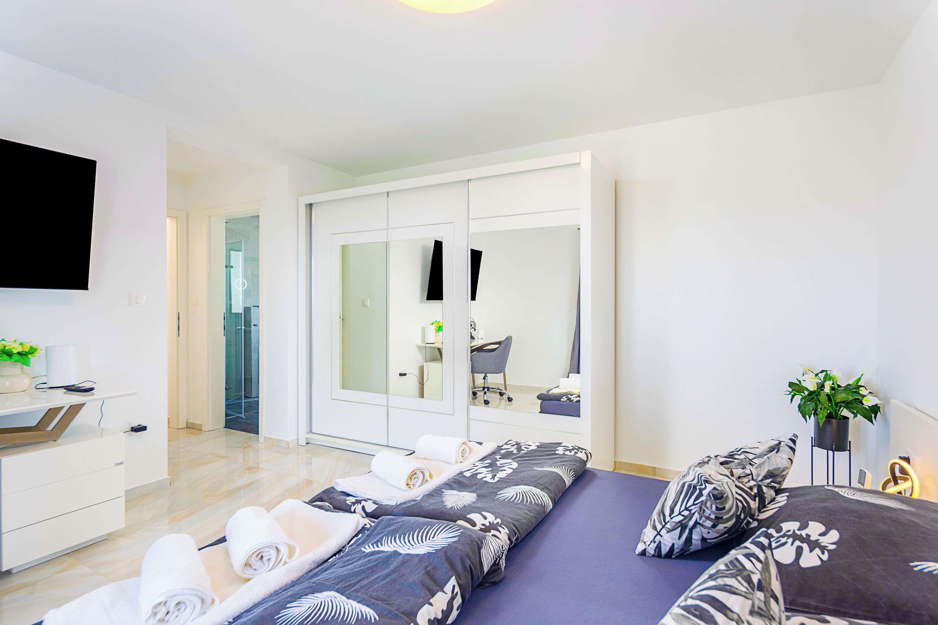 Un dormitorio moderno con cama, escritorio, armario y televisor.