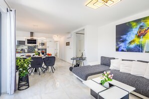Un salon moderne comprenant un canapé, une table basse et un coin repas avec des chaises.