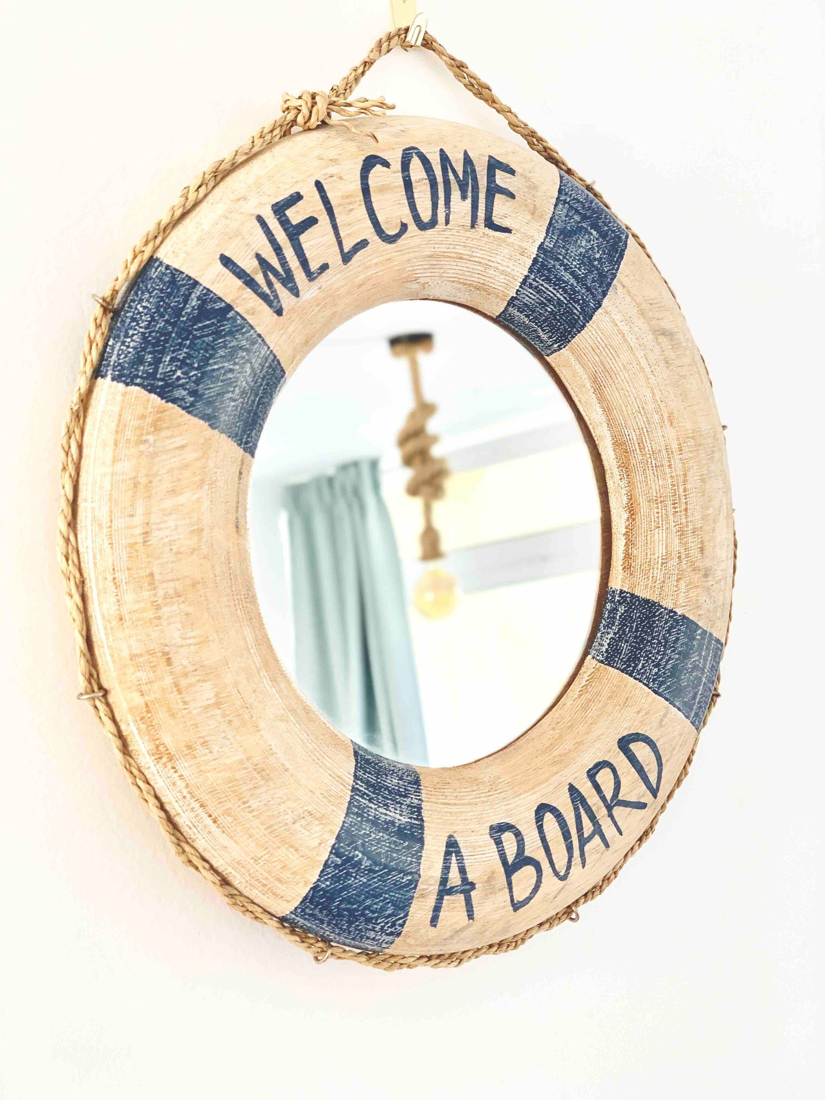 En rund træskilt med teksten 'WELCOME A BOARD'.