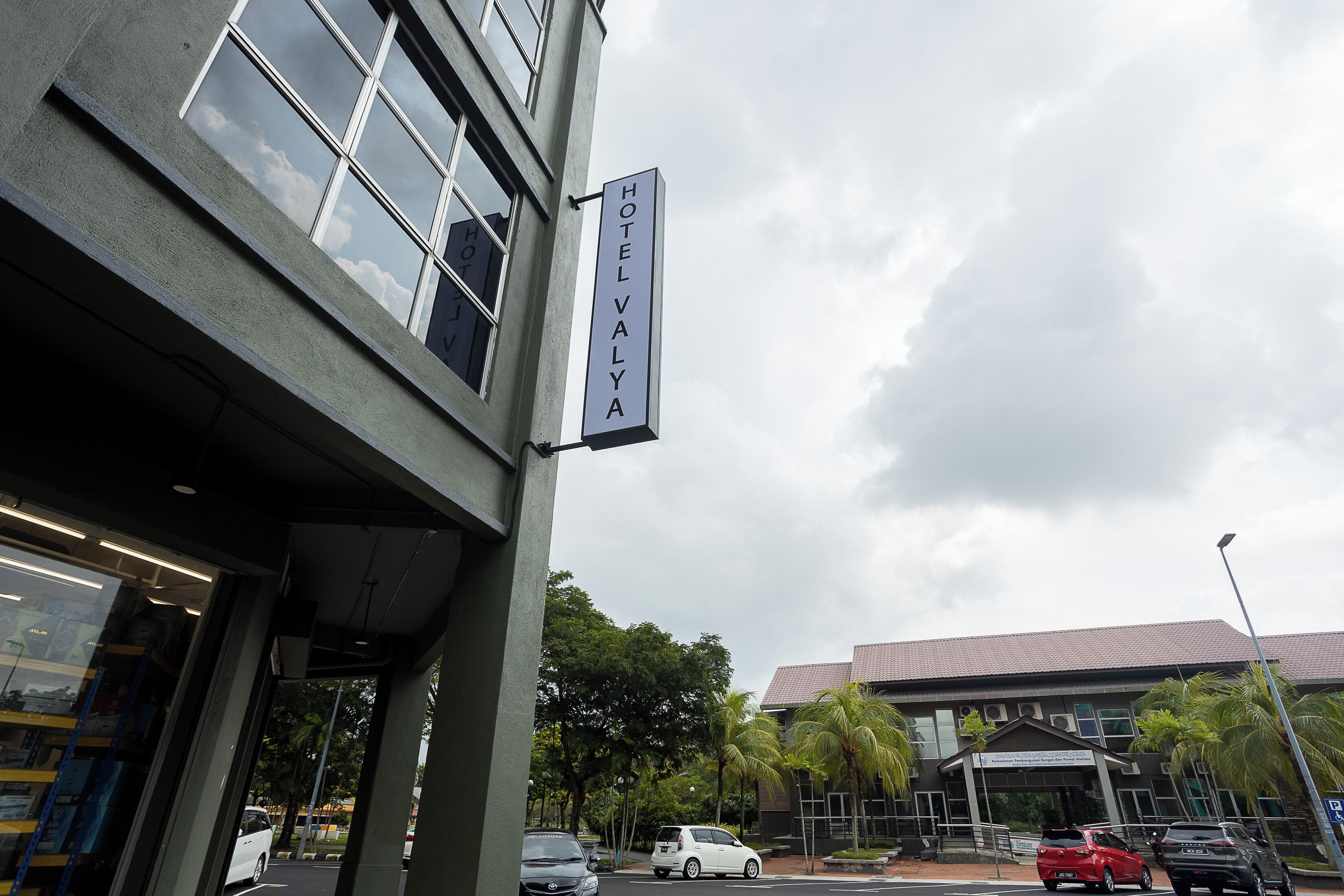 Un hotel con un cartel que dice 'HOTEL VALYA' y un edificio moderno con techo de tejas y unidades de aire acondicionado.