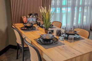 A dining table set with black plates, bowls, and cutlery, accompanied by a vase with plants and a water bottle. - HOTEL VALYA MELAKA SENTRAL RIVERFRONT (Malacca City)
