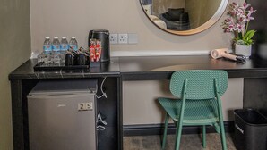 A compact hotel room with a kitchenette, a round mirror, a small refrigerator, a green chair, and a potted plant. - HOTEL VALYA MELAKA SENTRAL RIVERFRONT (Malacca City)