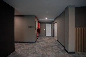 A hallway with a carpeted floor, a fire extinguisher, and a door at the end. - HOTEL VALYA MELAKA SENTRAL RIVERFRONT (Malacca City)