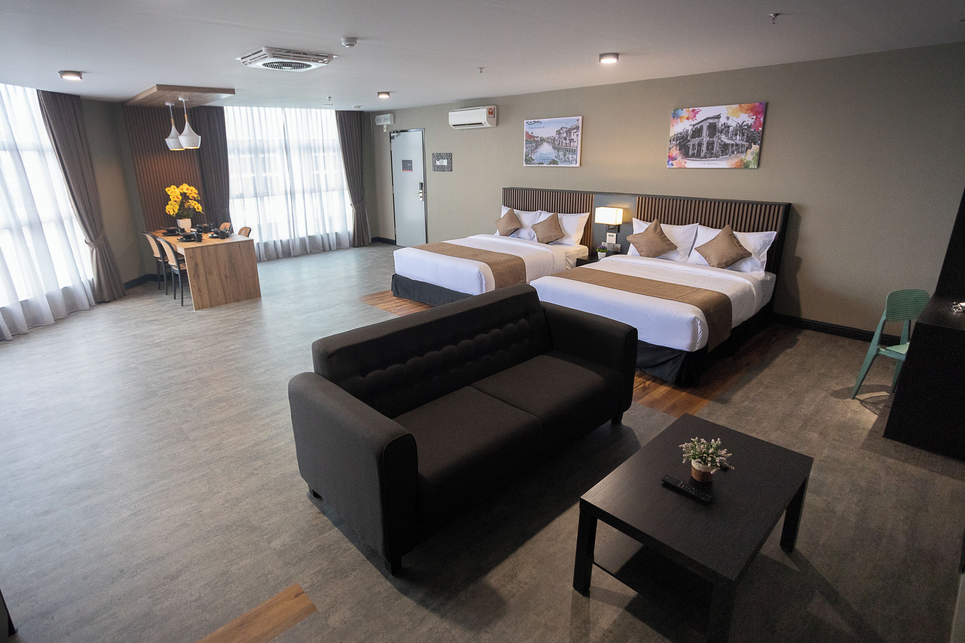 Ein Hotelzimmer mit zwei Betten, einer Couch, einem kleinen Tisch und einem Schreibtisch.