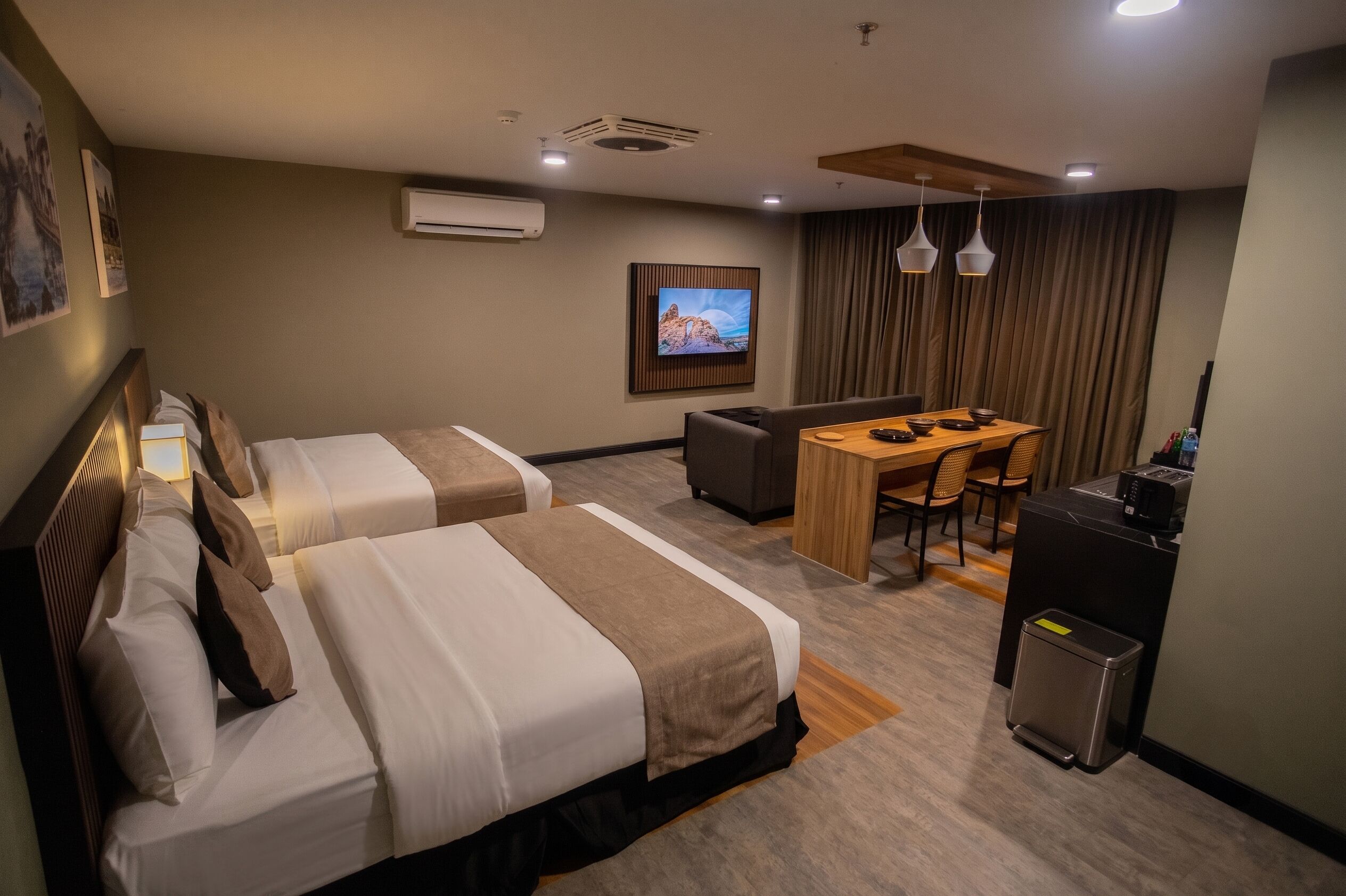 A hotel room with two beds, a desk, a television, and a minibar.
