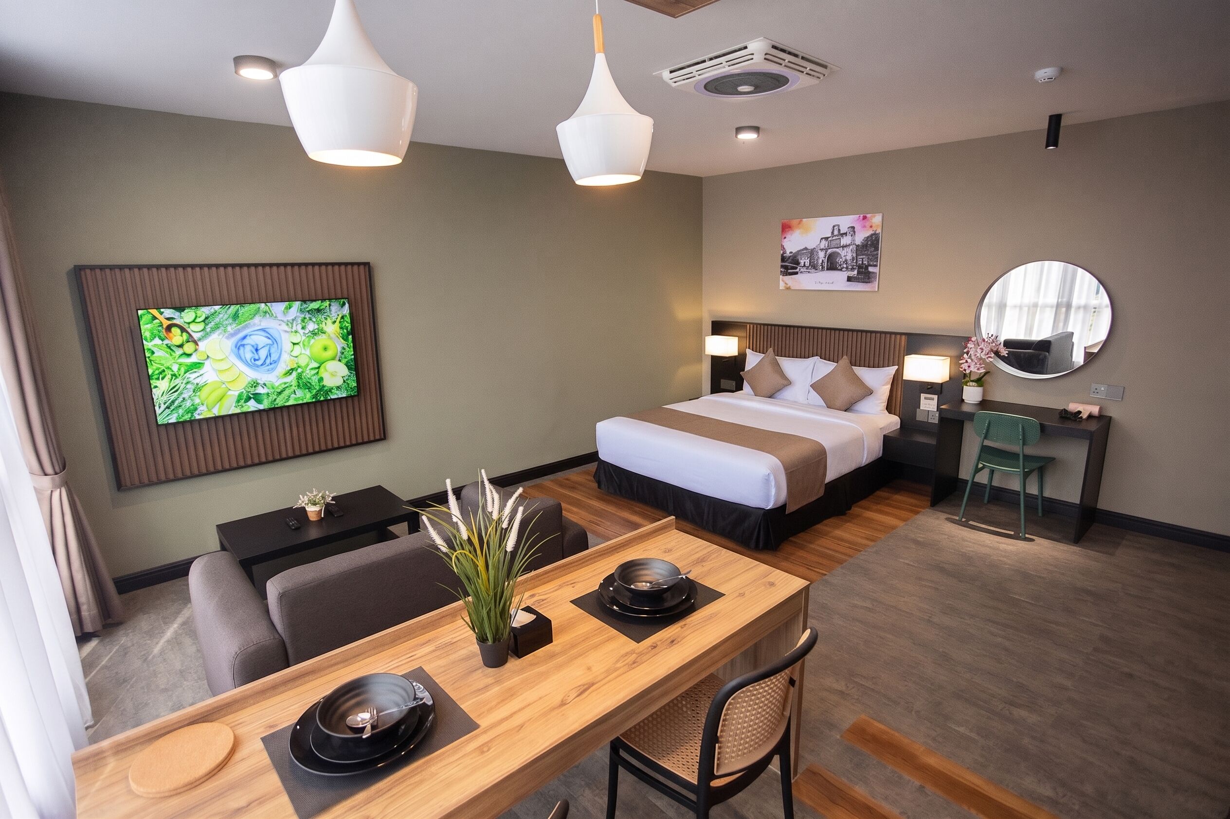 A hotel room with a bed, a desk with a chair, a television, and a dining table set for two.