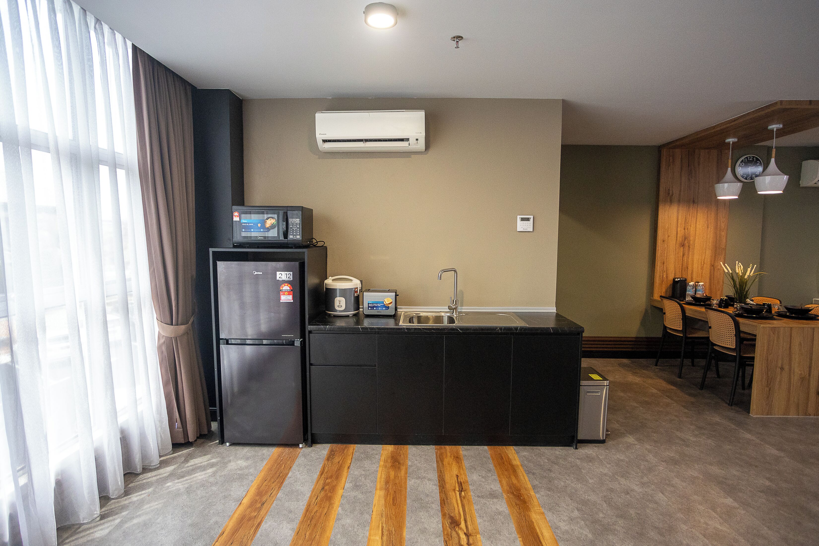 Una cocina compacta equipada con refrigerador, microondas, tostadora y lavadero.