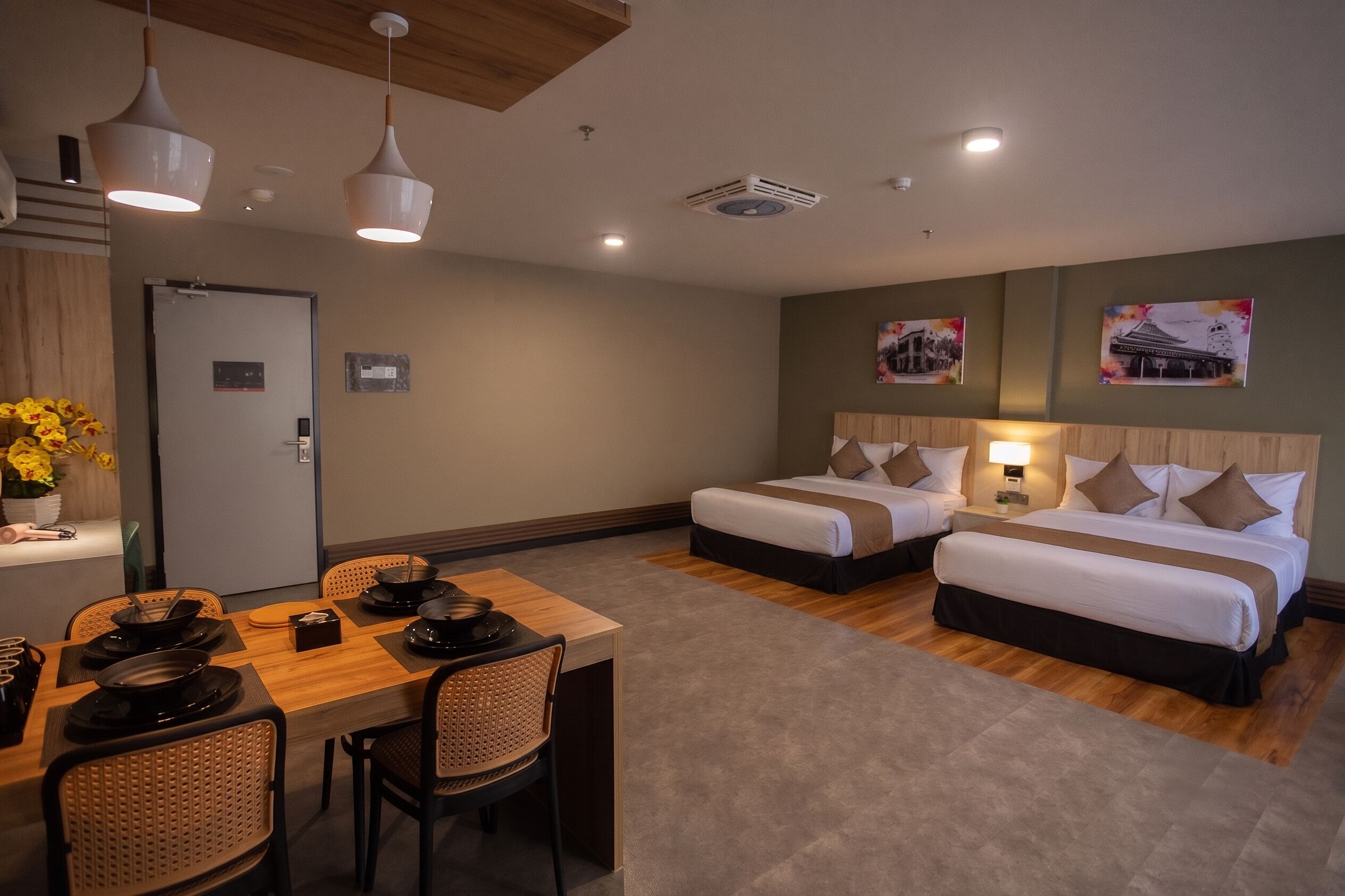 Une chambre d’hôtel avec deux lits, une table à manger avec des chaises et un petit coin cuisine.