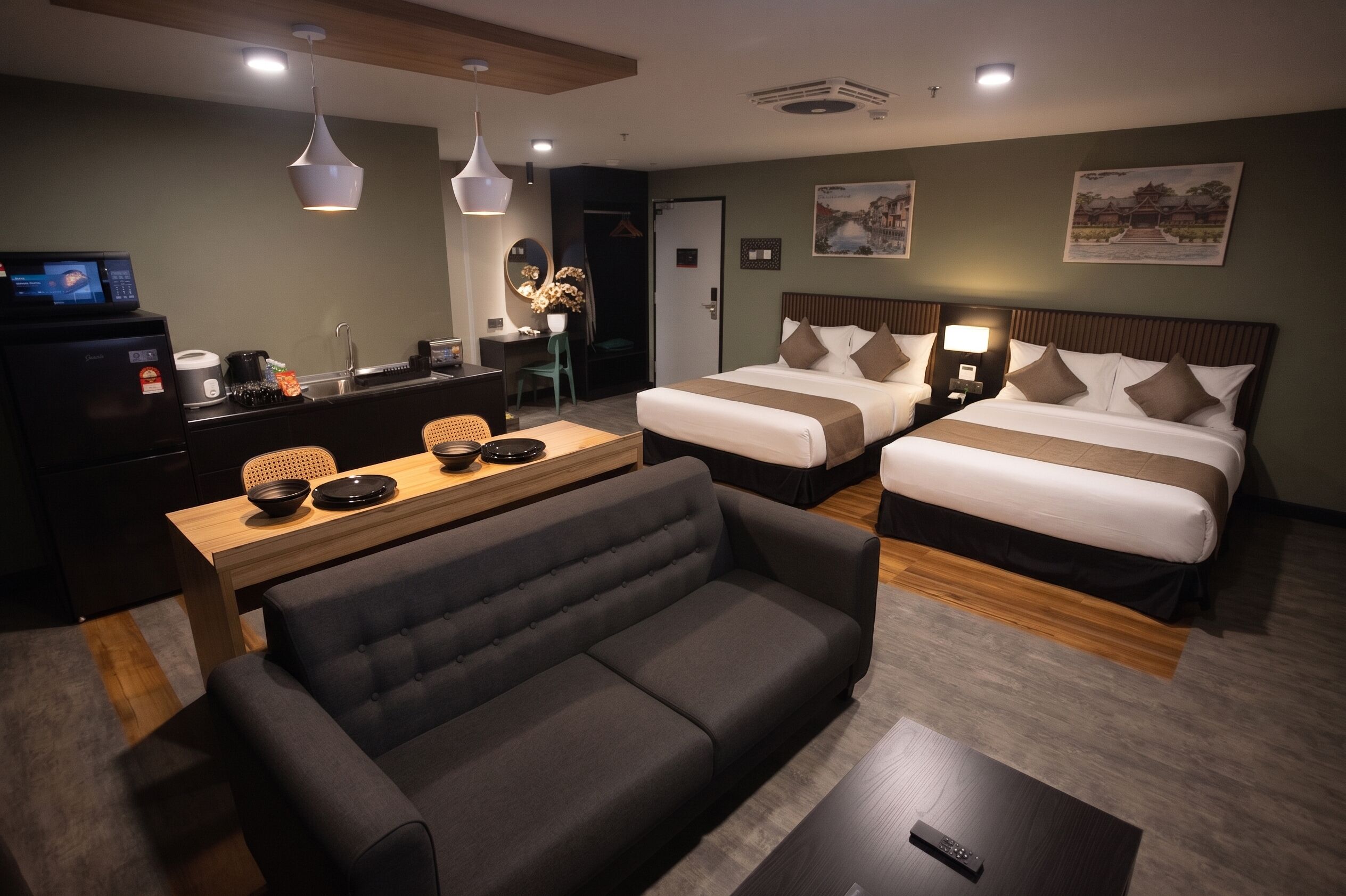 Habitación de hotel con sofá, dos camas, escritorio con cafetera y televisión.
