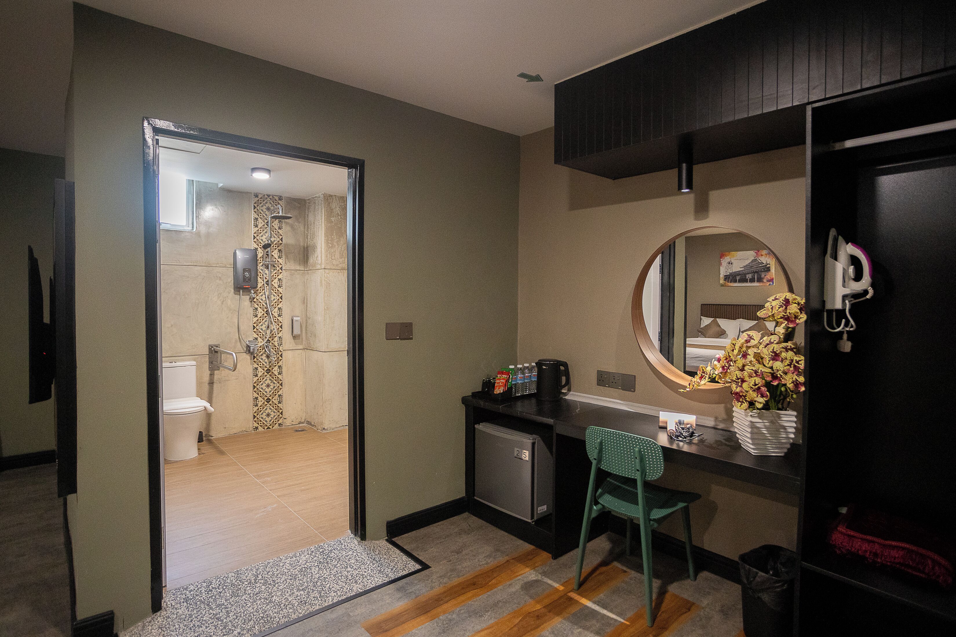 Une chambre d’hôtel équipée d’une douche, de toilettes, d’un bureau, d’une chaise et d’un petit réfrigérateur.