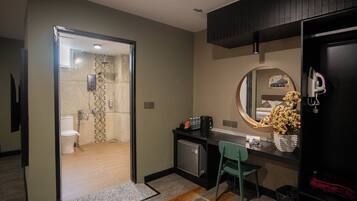 Une chambre d’hôtel équipée d’une douche, de toilettes, d’un bureau, d’une chaise et d’un petit réfrigérateur.