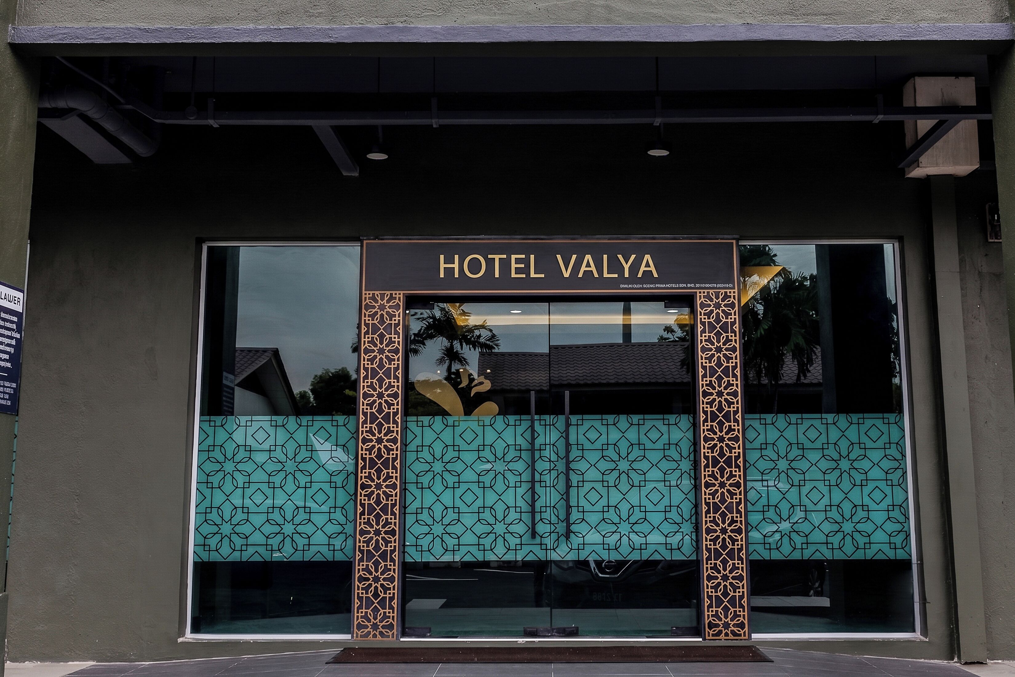 L’entrée de l’hôtel Valya se distingue par sa grande façade en verre, une enseigne au-dessus de l’entrée et des panneaux décoratifs de part et d’autre.