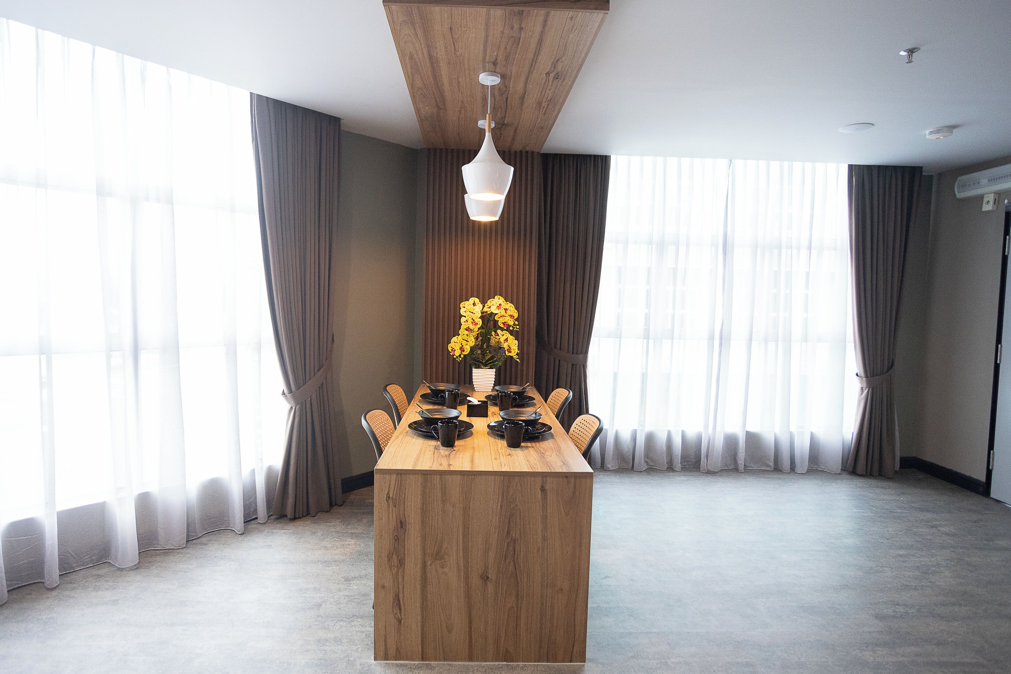 Un comedor moderno con mesa de madera, sillas y una lámpara colgante.