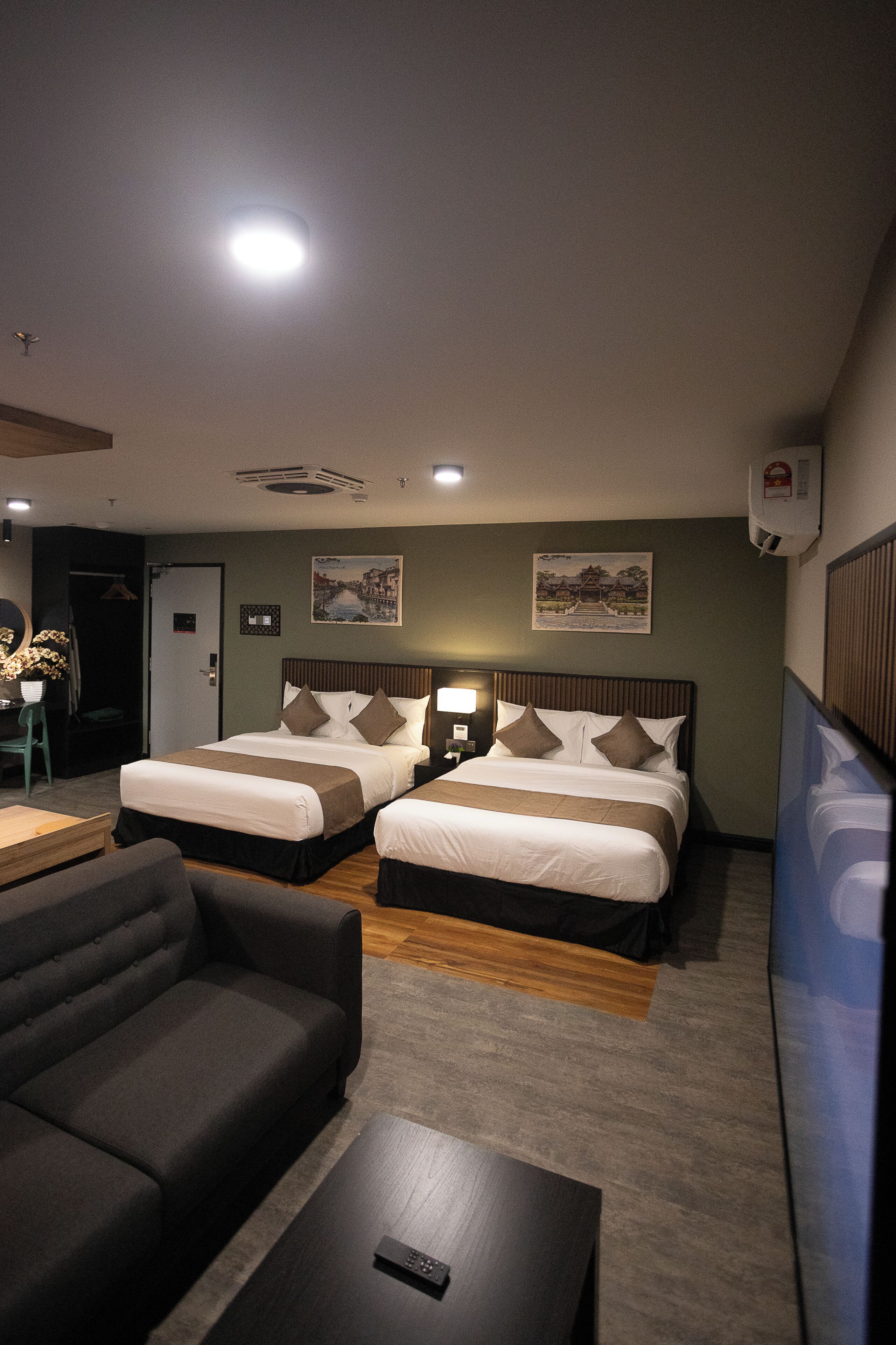 Habitación de hotel con dos camas, un sofá, un televisor y una mesita.