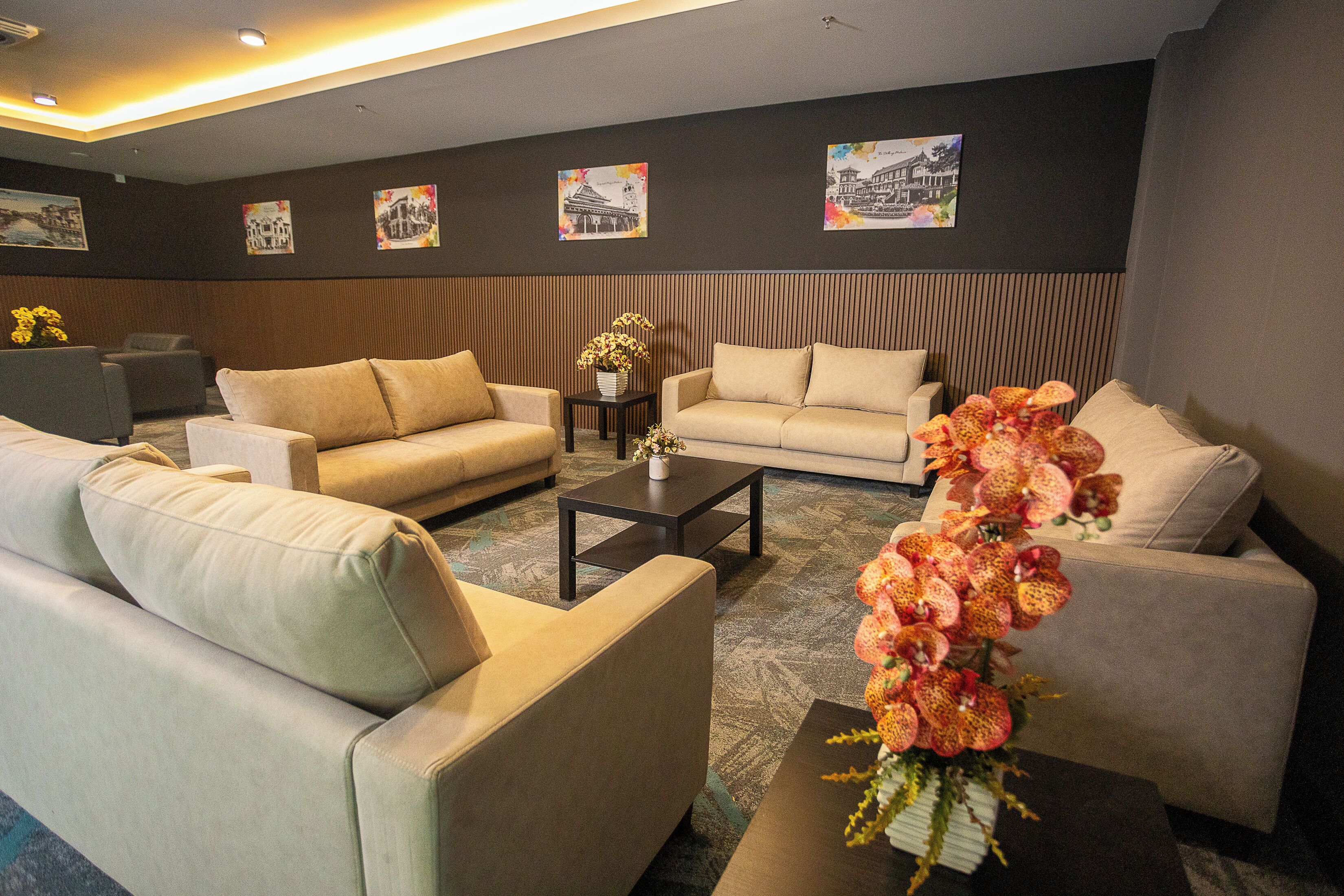 A modern living room with two sofas, a coffee table, and a decorative orchid arrangement.
