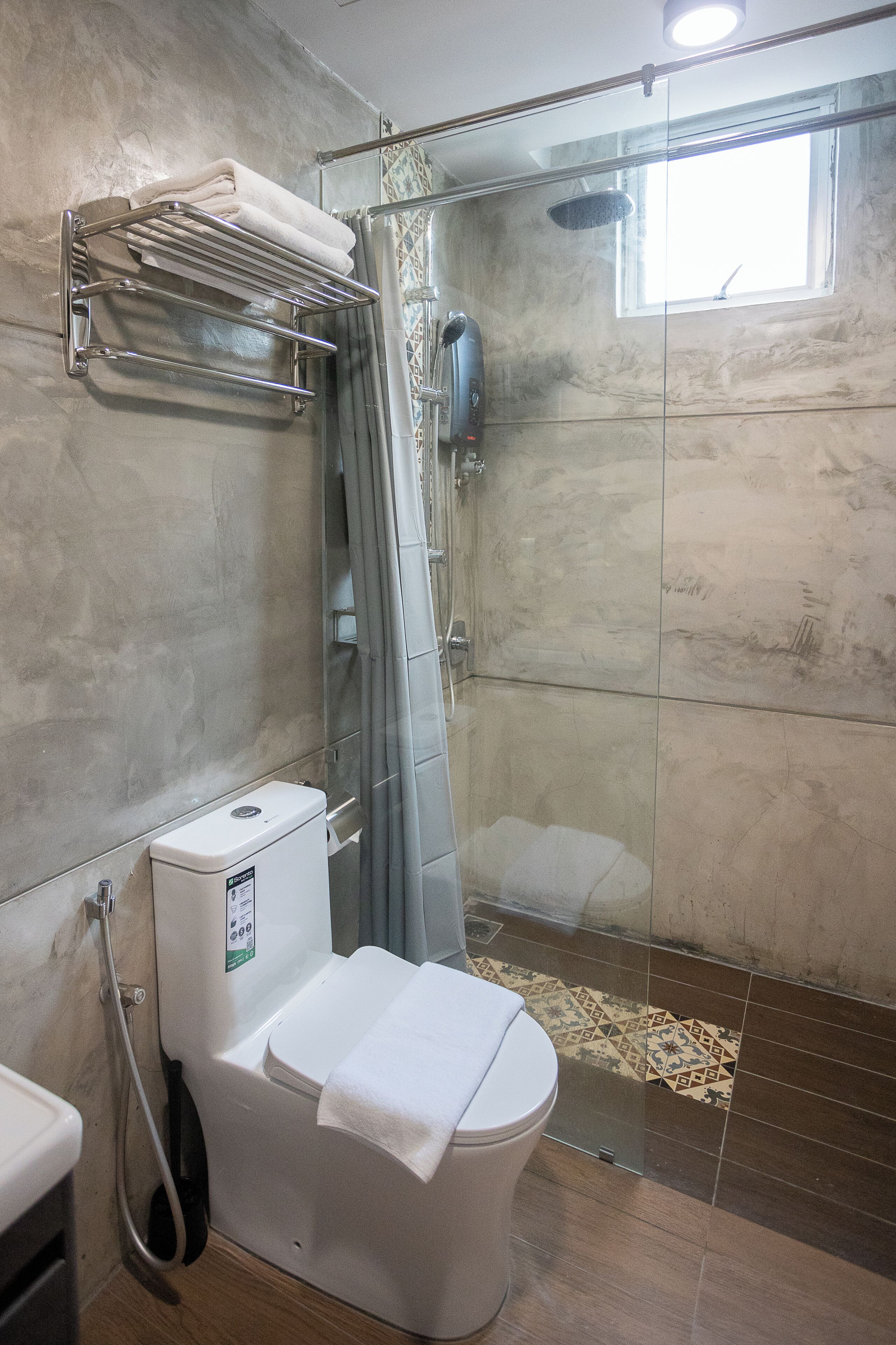 Un baño con ducha, inodoro y un perchero para toallas.